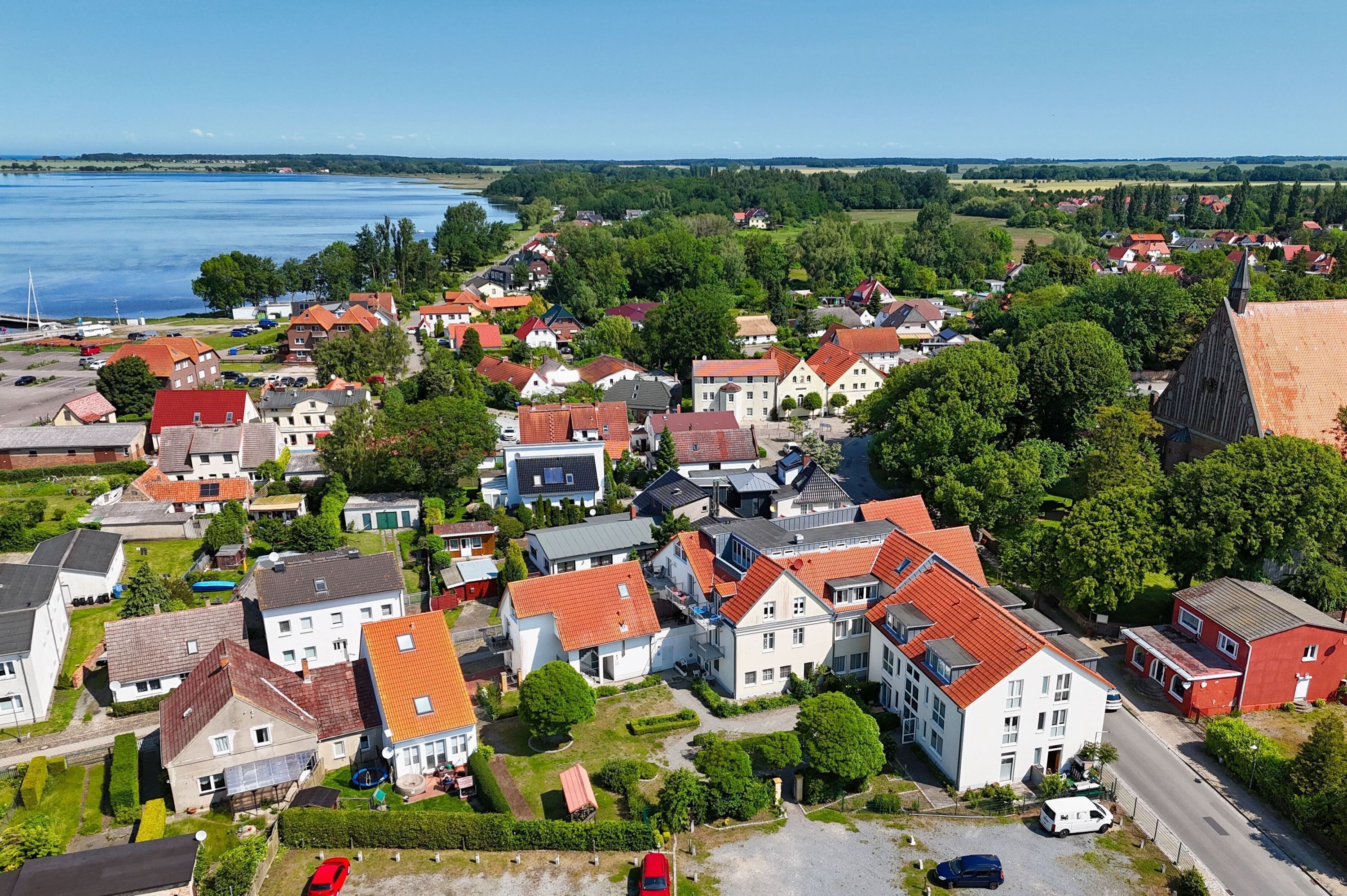 A residential area with houses, a road, and a body of water in the background.