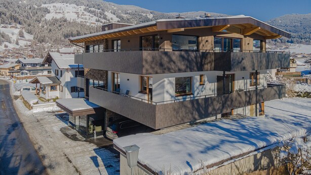 A modern multi-story building with a flat roof, large windows, and a balcony. - Apartment in Brixen im Thale With Parking (Brixen im Thale)
