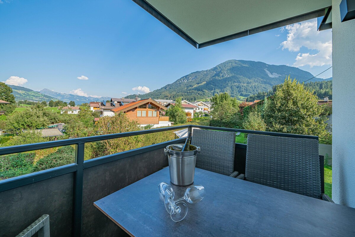 A balcony with a table, a metal bucket, and a wine glass.