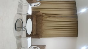 A compact hotel room with a bed, a small table, a chair, a mirror, a wooden cabinet, and a built-in wardrobe.