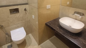A bathroom with a white toilet, a sink with a mirror, and tiled walls.