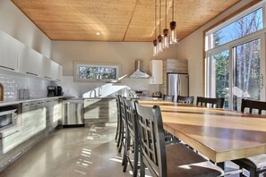 A modern kitchen with a central island, stainless steel appliances, and large windows.
