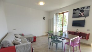 Una sala de estar moderna con un sofá, mesa de comedor, sillas y televisión.
