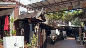 A courtyard with a covered seating area, potted plants, and a sign for La Maison du Laos. - La MaiSon Du laos Hotel (Luang Prabang)