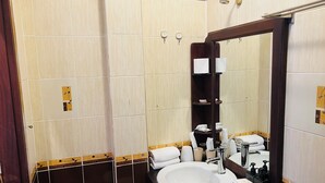 A bathroom with a white sink, dark brown tiles, a large mirror, and a shower area. - La MaiSon Du laos Hotel (Luang Prabang)