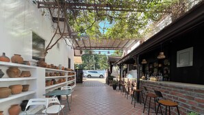 An outdoor patio area with terracotta tiles, white chairs, and a bar area with stools. - La MaiSon Du laos Hotel (Luang Prabang)