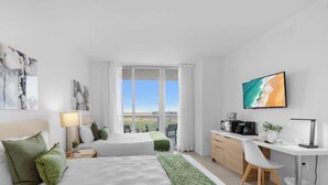 A hotel room with two beds, a desk, and a view of the city. - Unique 2BR Apartment Gym & Pool (Hallandale Beach)