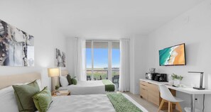 Habitación de hotel con dos camas, un escritorio, cafetera y vista a la ciudad.