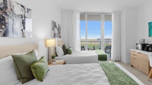A hotel room with two beds, a desk, a coffee maker, and a view of the city. - Spectacular Studio with pool and Amenities (Hallandale Beach)