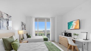 Une chambre d’hôtel avec deux lits, un bureau et une vue sur la ville.