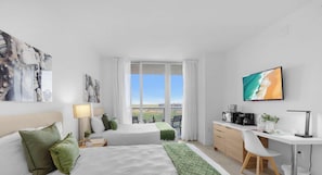 Une chambre d’hôtel avec deux lits, un bureau, une machine à café et une vue sur la ville.