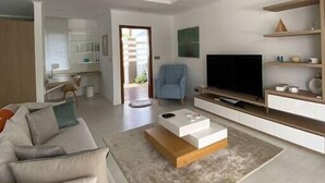 A modern living room with a sofa, coffee table, TV, and a ceiling fan. - Villa BIJOU, 3 bed, grand bay center by Immoclair (Rivière du Rempart District)