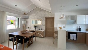 A modern kitchen with white cabinets, a wooden dining table, and a large window. - Villa BIJOU, 3 bed, grand bay center by Immoclair (Rivière du Rempart District)