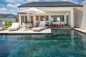 A modern outdoor pool area with lounge chairs and a covered seating area.