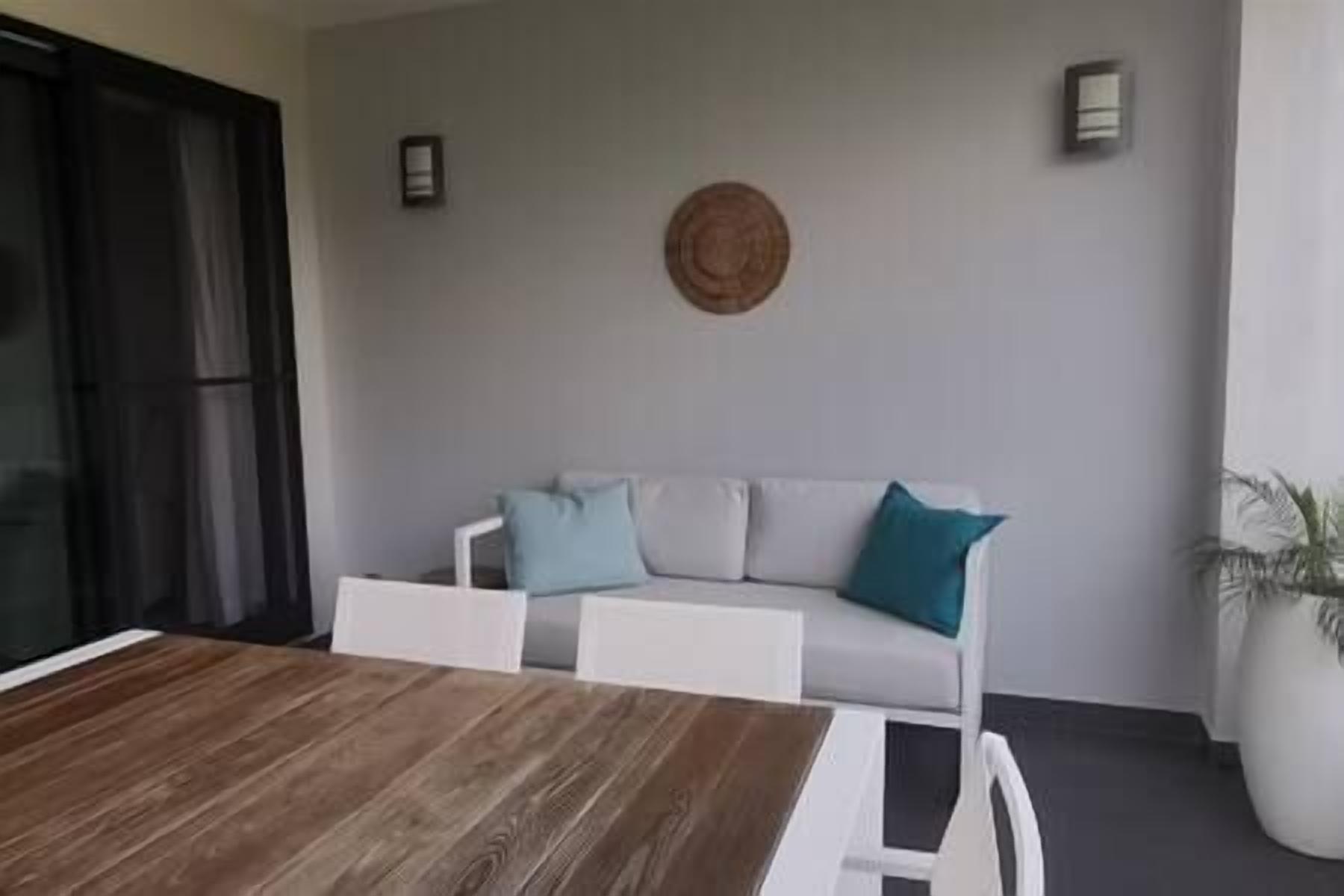 A dining area with a wooden table and chairs, a white sofa with cushions, and a round wall decoration.