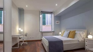 A bedroom with a bed, bedside table, lamp, desk, chair, and a window. - Libeccio - Style and Comfort at Two Steps from the Cathedral (Genova)