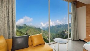 A room with a large sliding glass door leading to a mountain view. - MV Acosta by Lawrence hotels (Mussoorie)