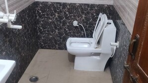 A small bathroom with a toilet, a sink, and a mirror on the wall. - Giriraj kripa (Vrindavan)