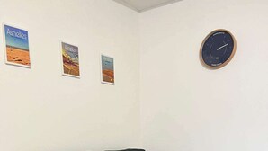 A corner room with a grey sofa, a small round table, and three framed pictures on the wall. - La maison d'Oscar, 200m plage (Asnelles)