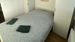 A bedroom with a bed, a hanging light fixture, a door, and a wall-mounted picture. - La maison d'Oscar, 200m plage (Asnelles)