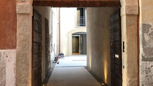 Un estrecho callejón con paredes de piedra y puertas de madera, que conduce a la entrada de un edificio.
