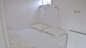 A small, single-bed room with white bedding, a window with a view, and a radiator.