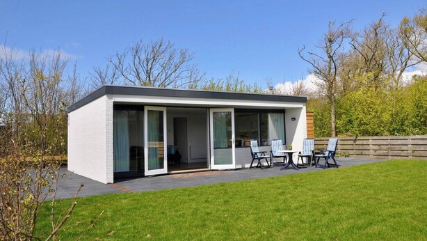 A modern house with a patio area featuring outdoor furniture.
