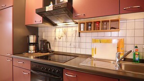 Ett modernt kök med vitvaror i rostfritt stål, en inbyggd ugn och en kaffebryggare.