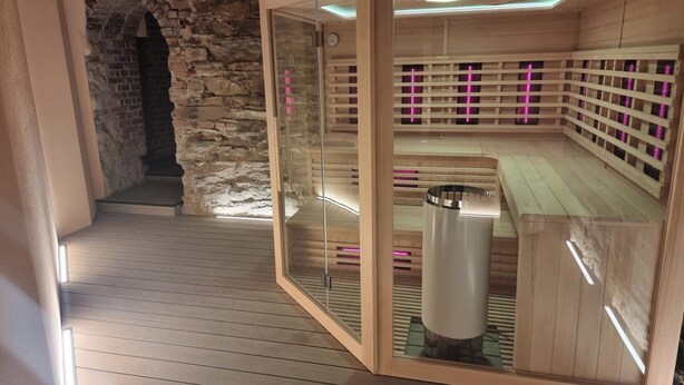 Un sauna avec des bancs en bois et des murs en verre, un mur en pierre et un plancher en bois.