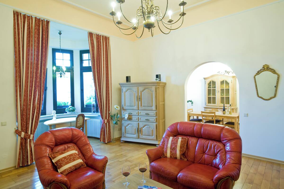 Una sala de estar con dos sillones de cuero, un aparador y una zona de comedor con mesa y sillas.