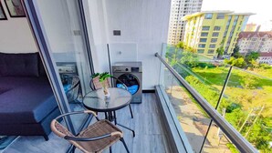 A balcony with a sofa, a round table, and two wicker chairs. - Staroot Residences- Celestial Chalet (Nairobi)