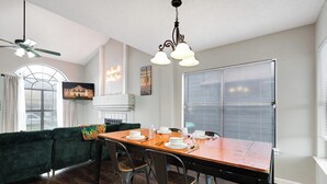 A dining area with a wooden table set for six, a green sofa, and a ceiling fan.