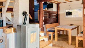 Interior acogedor de una cabaña con chimenea de leña, una mesa de comedor y un banco.