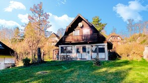 Una casa de dos pisos con balcón, un porche delantero y un garaje visible.