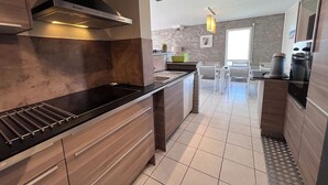 A modern kitchen with a black countertop, stainless steel range hood, and wooden cabinets.