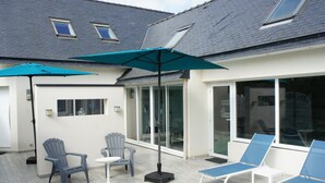 A patio area with outdoor seating, including chairs and a table, under a large umbrella.