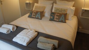 A neatly made bed with pillows labeled "SEA" and a set of towels on the bed.