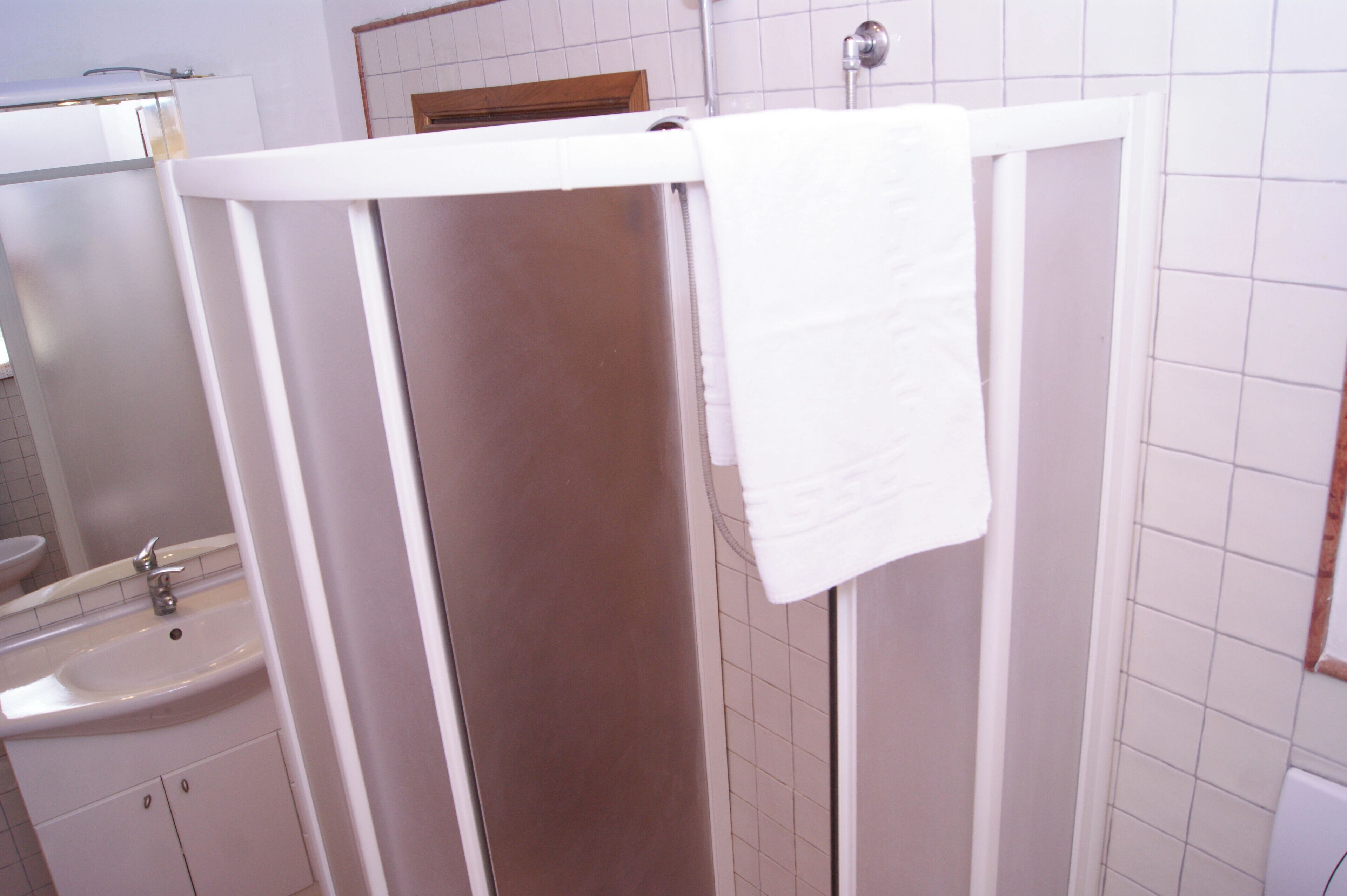 A bathroom with a white sink, mirror, and shower enclosure.