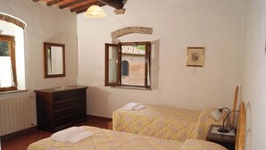 Un dormitorio con dos camas, un aparador, una ventana con vista a un edificio de ladrillo y un cuadro en la pared.