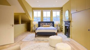 Un dormitorio con una cama grande, chimenea y vistas por la ventana.