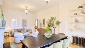 Un comedor con una mesa de madera oscura, sillas tapizadas en verde y un florero con plantas.