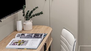 Una silla de oficina moderna con respaldo alto y ruedas, ubicada al lado de un escritorio de madera con una revista y una planta en maceta.