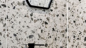 Un baño con un lavamanos blanco, un grifo negro y un espejo con marco negro.