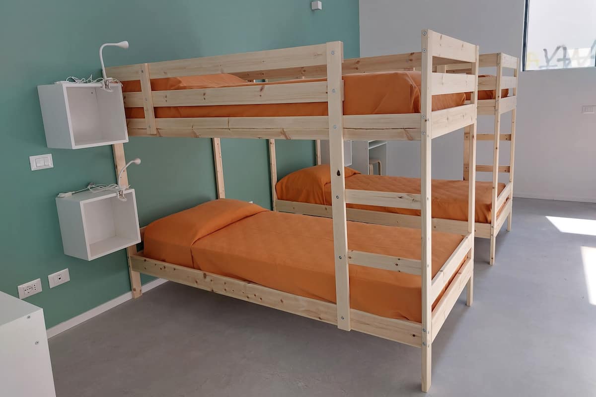 A bunk bed room with teal walls, a white bedside table, and a small white cabinet.
