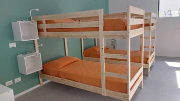 A bunk bed room with teal walls, a white bedside table, and a small white cabinet.