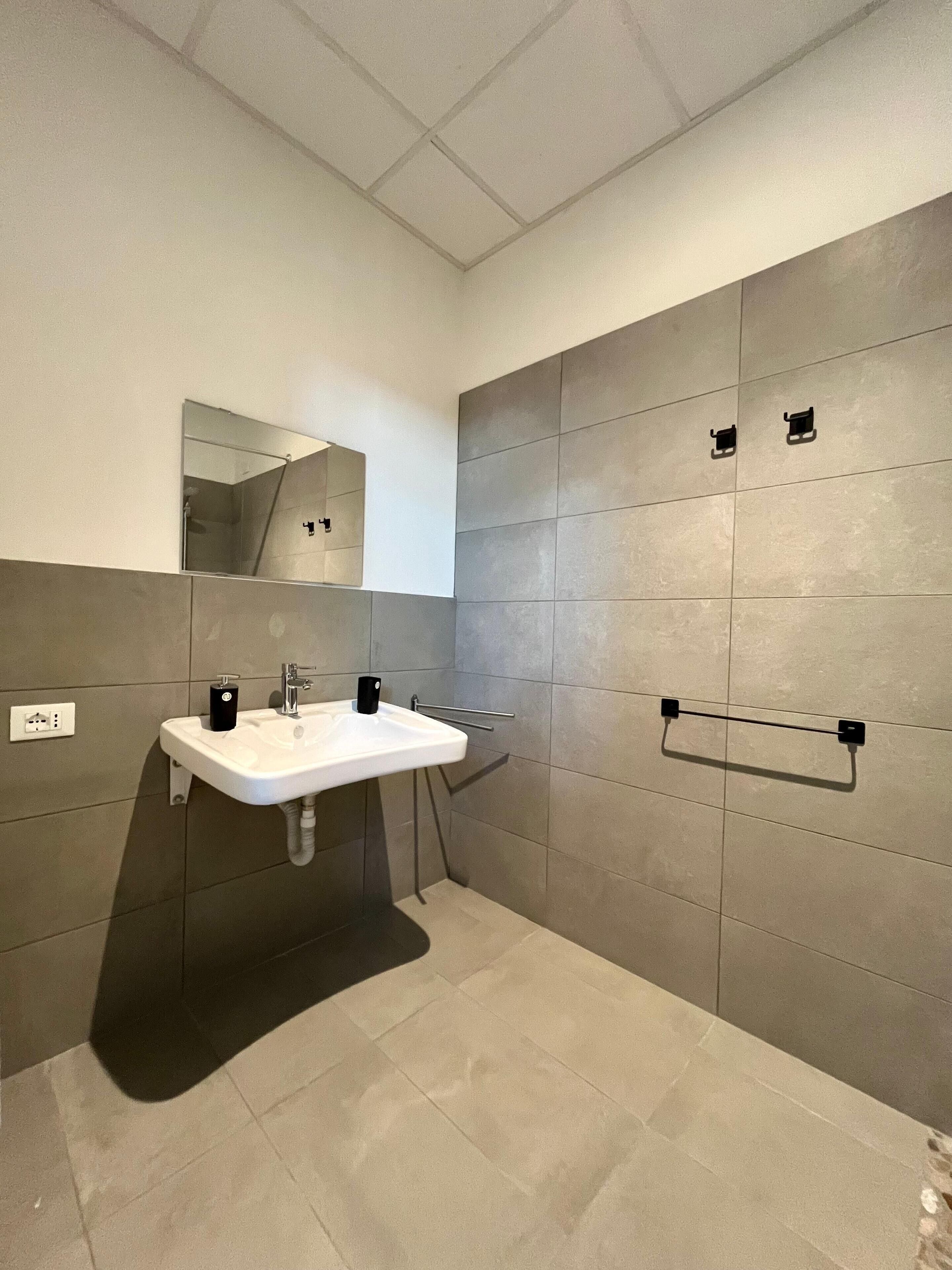 A modern bathroom with a white sink, a mirror, and a towel rack.