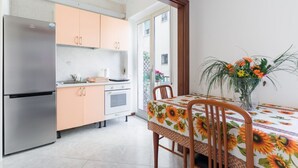Eine Küche mit Kühlschrank, Schränken und einem Esstisch mit Stühlen.