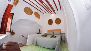 A compact bedroom with a bed, a small table, and a window with a red shutter. - Casa Frasquita, en el casco histórico de Cehegín (Cehegín)