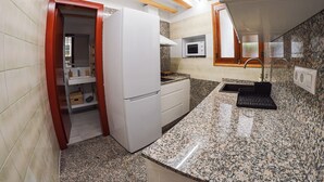 A compact kitchen with a refrigerator, microwave, and granite countertop. - Casa Frasquita, en el casco histórico de Cehegín (Cehegín)