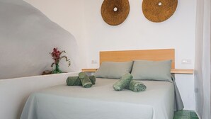 A neatly made bed with green linens, a wooden headboard, and two woven wall decorations. - Casa Frasquita, en el casco histórico de Cehegín (Cehegín)